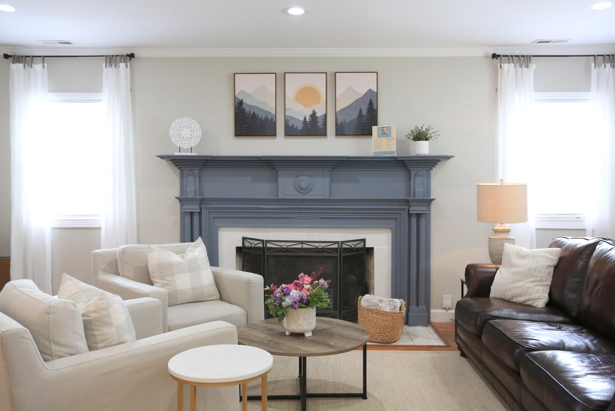 TN Mental Wellness inside office with two white chairs and one brown counch in front of light blue fireplace and two sun-lit windows